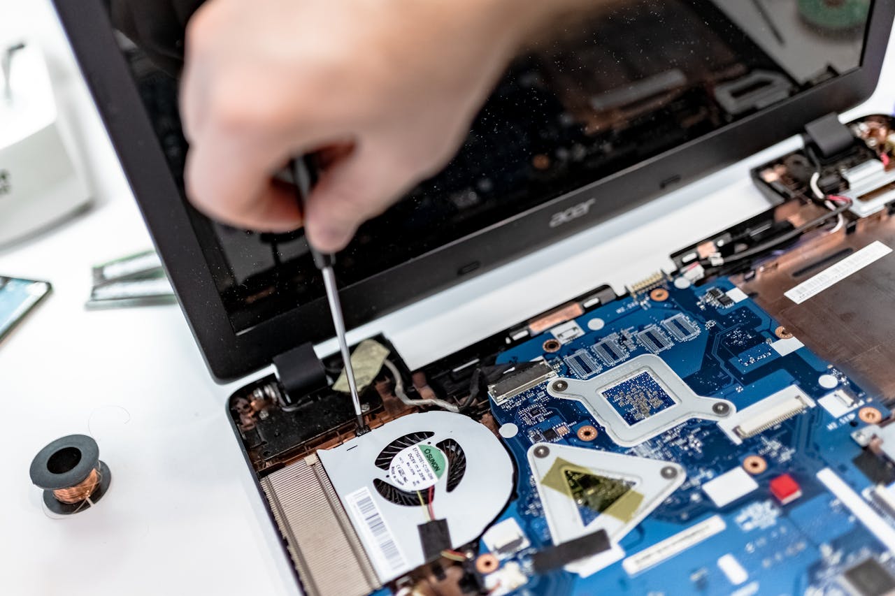services-02 Technician repairing a laptop motherboard, focusing on electronic components.