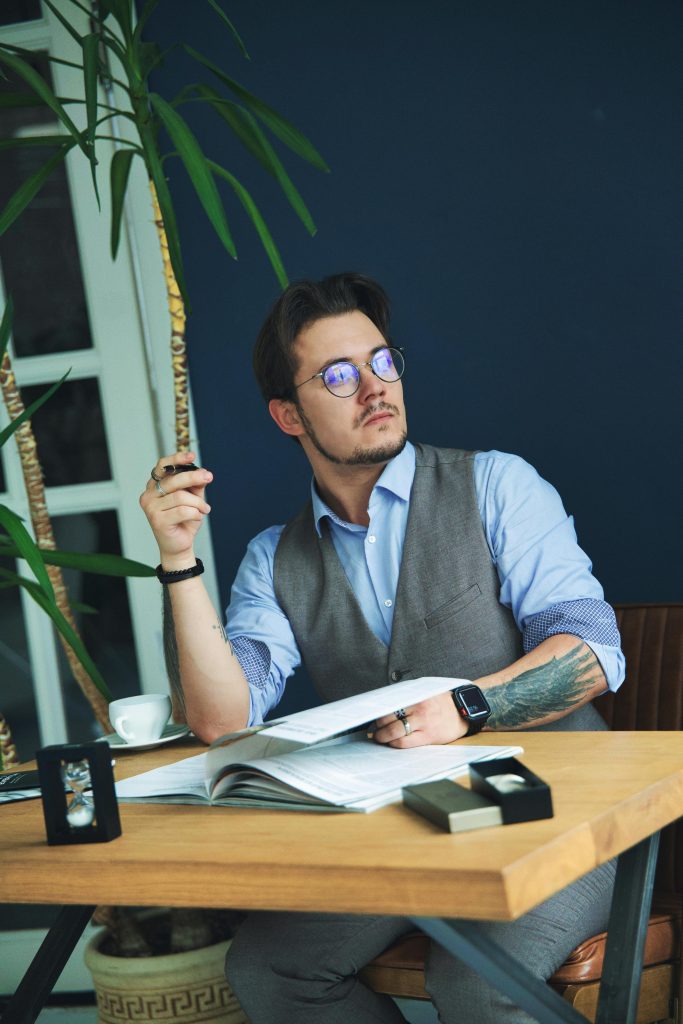 Contemplative man in modern office setting, writing at a desk.